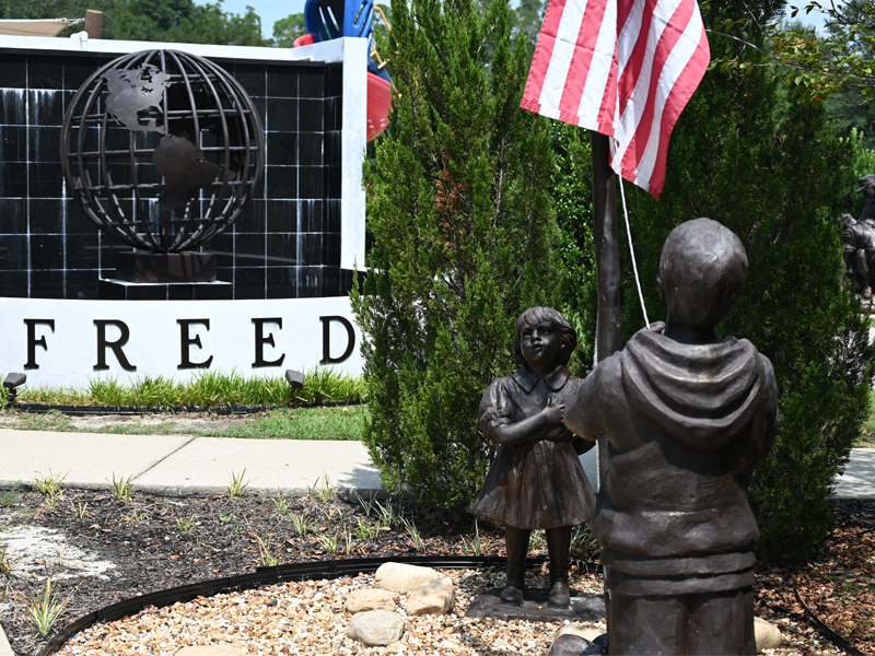 Image of park with sculptures depicting children with the American Flag.
